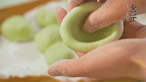 將均分的艾草面團(tuán)搓成圓，挖一個(gè)窩，放入餡心，再搓成圓。