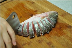 將鱸魚(yú)清洗干凈，從脊椎處切斷至腹部，腹部保留1cm左右不要切斷。
