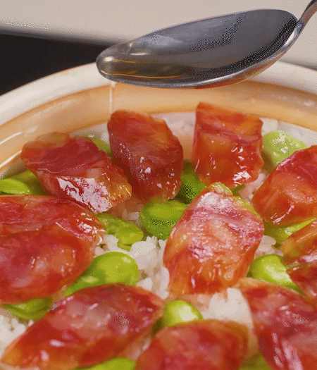 大米出現(xiàn)小孔時開蓋放香腸，往鍋邊淋入少許油，再燜煮8~10分鐘左右。