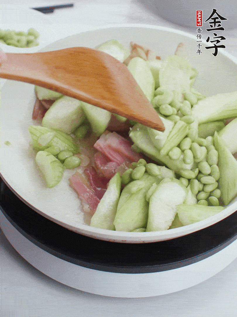 依次下絲瓜、青豆翻炒，炒至絲瓜打蔫縮小。