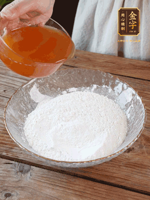 轉(zhuǎn)化糖漿、枧水、花生油攪拌均勻，加入面粉混合，醒發(fā)2小時(shí)。捏成23g一個(gè)的小球